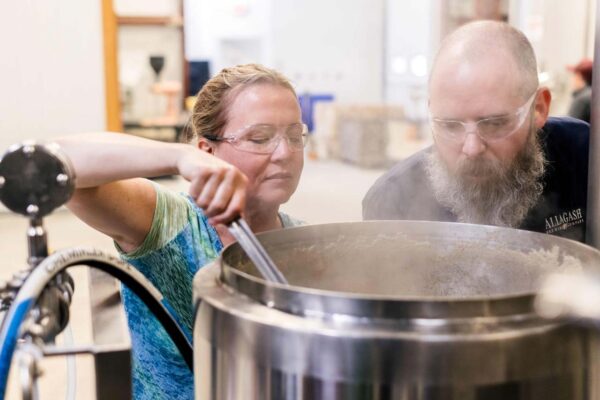 An HR team member and her brewer mentor brew on the Allagash pilot system.