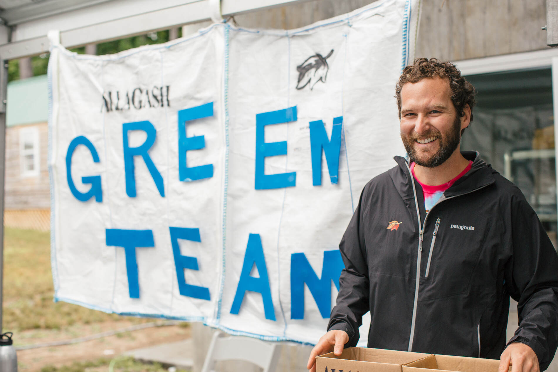 Member of the Allagash Green Team, standing in front of a poster.