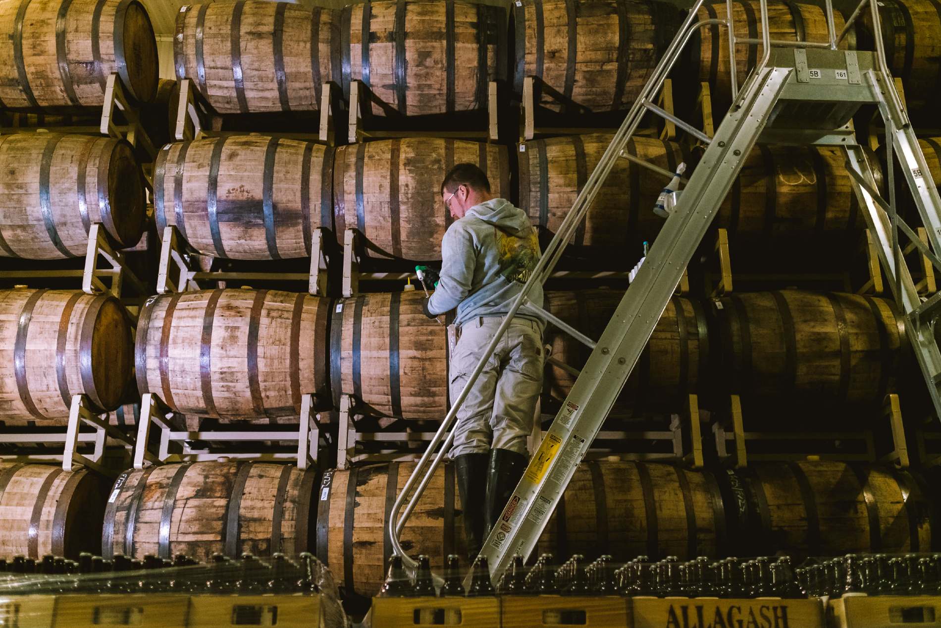 Allagash employee taking samples of beer from barrels of Curieux