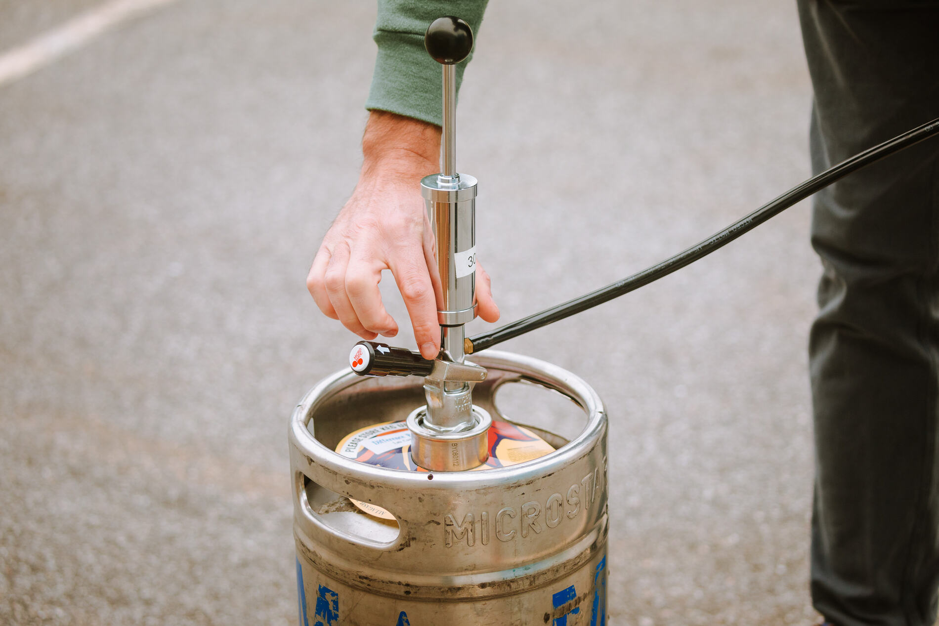 person holding a tap, about to tap a keg