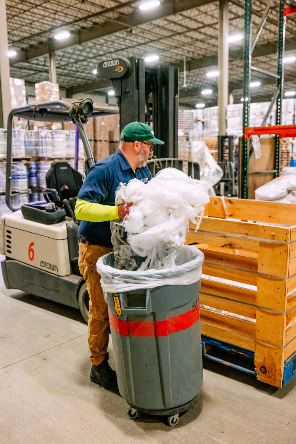 a person adding stretch wrap to a bin in preparation for it to be baled and shipped off for recycling