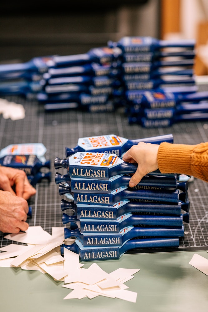 A stack of stickered tap handles for Allagash Surf House