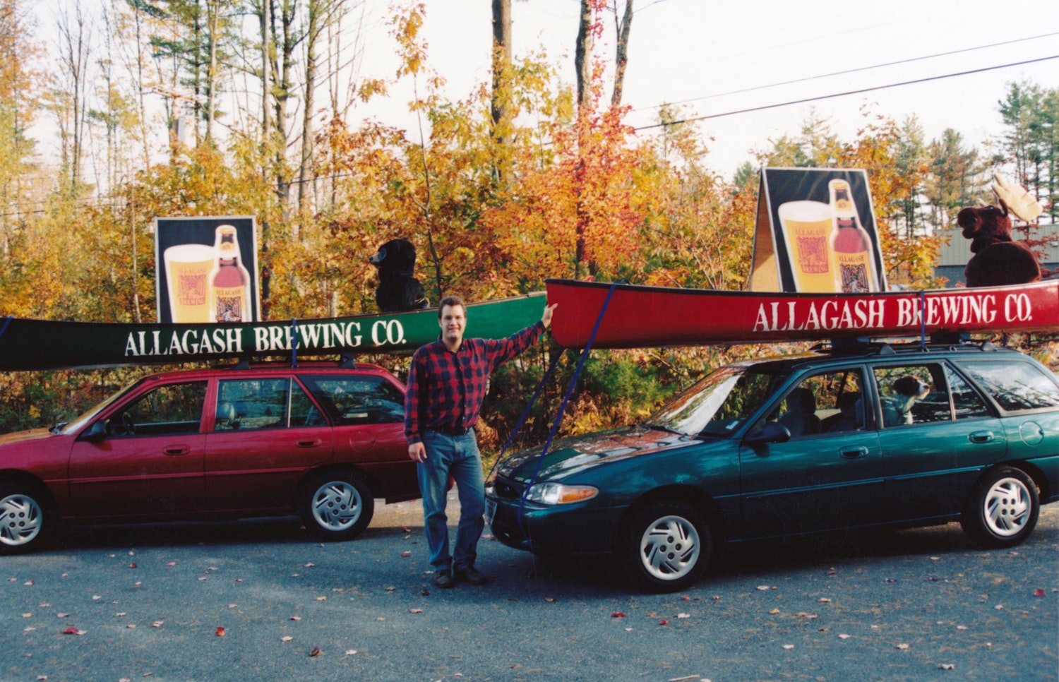 Rob Tod next to his first big marketing campaign - a stuffed moose and stuffed bear in canoes on a car.