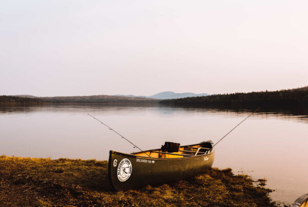 Canoe by a lake with fishing poles: adventure awaits.