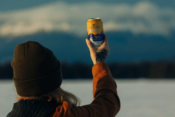 Person holds up a cold can of Allagash White