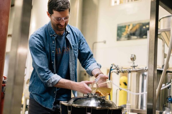 A member of the marketing team adds yeast to his pilot beer idea.
