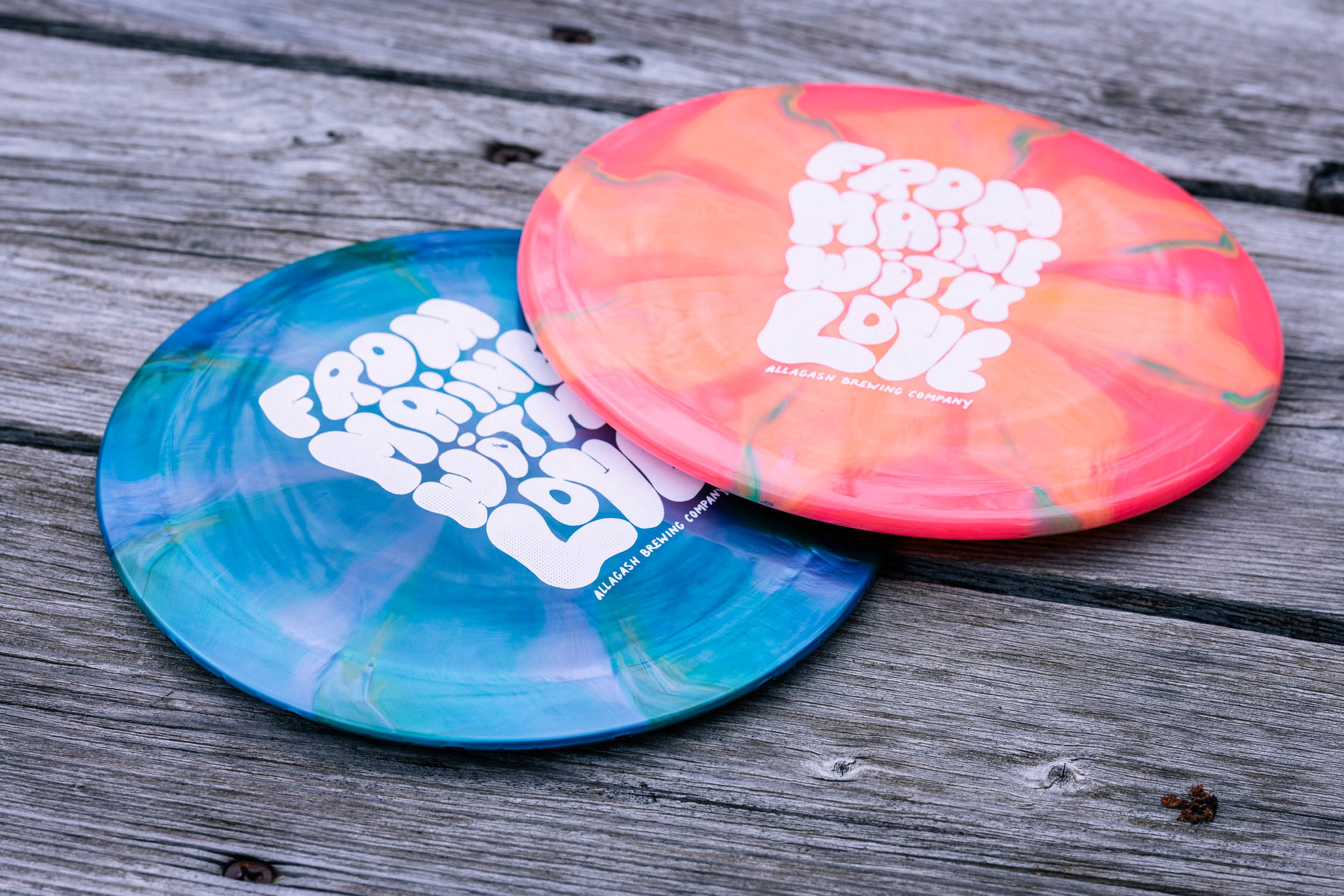 Allagash disc golf discs on a wooden table, lookin' all nice.